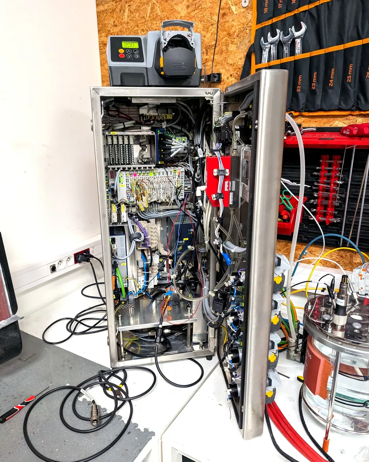 A bioreactor control tower opened on the QB Systems workbench during a retrofit, with its cabinet wiring, I/O modules and probe connections exposed